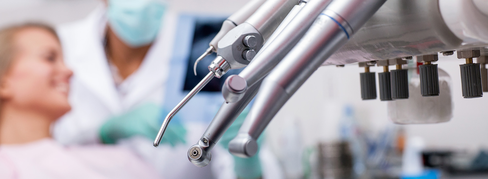 The image shows a dental office setting with a dentist working on a patient s mouth, surrounded by various dental equipment and tools.