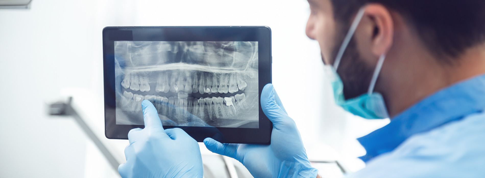 A dental professional examines a patient s teeth using a digital display.
