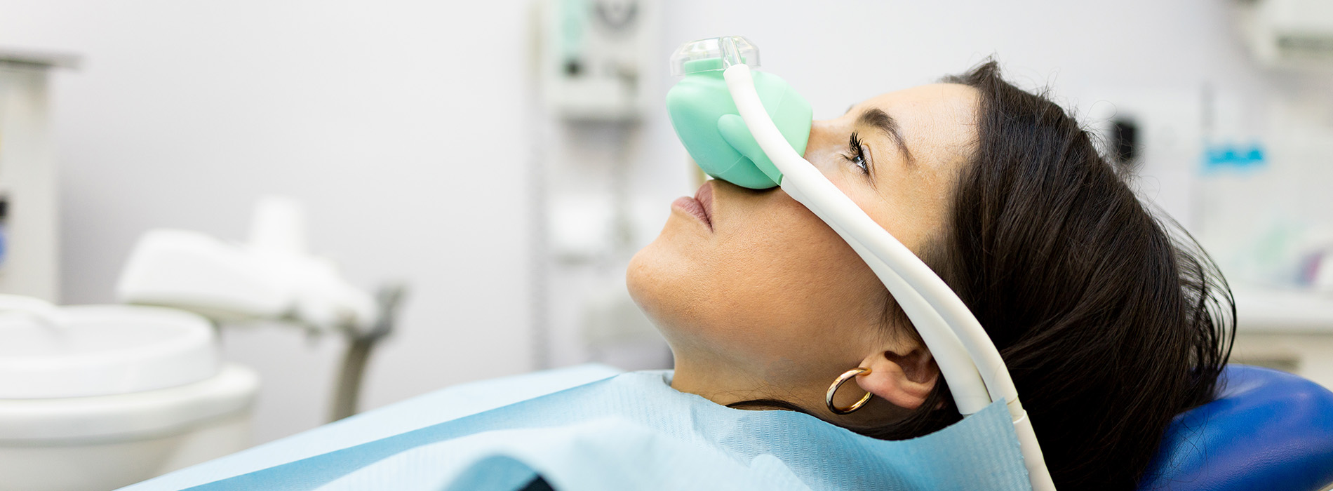 A woman wearing a medical oxygen mask while sitting in a dental chair.