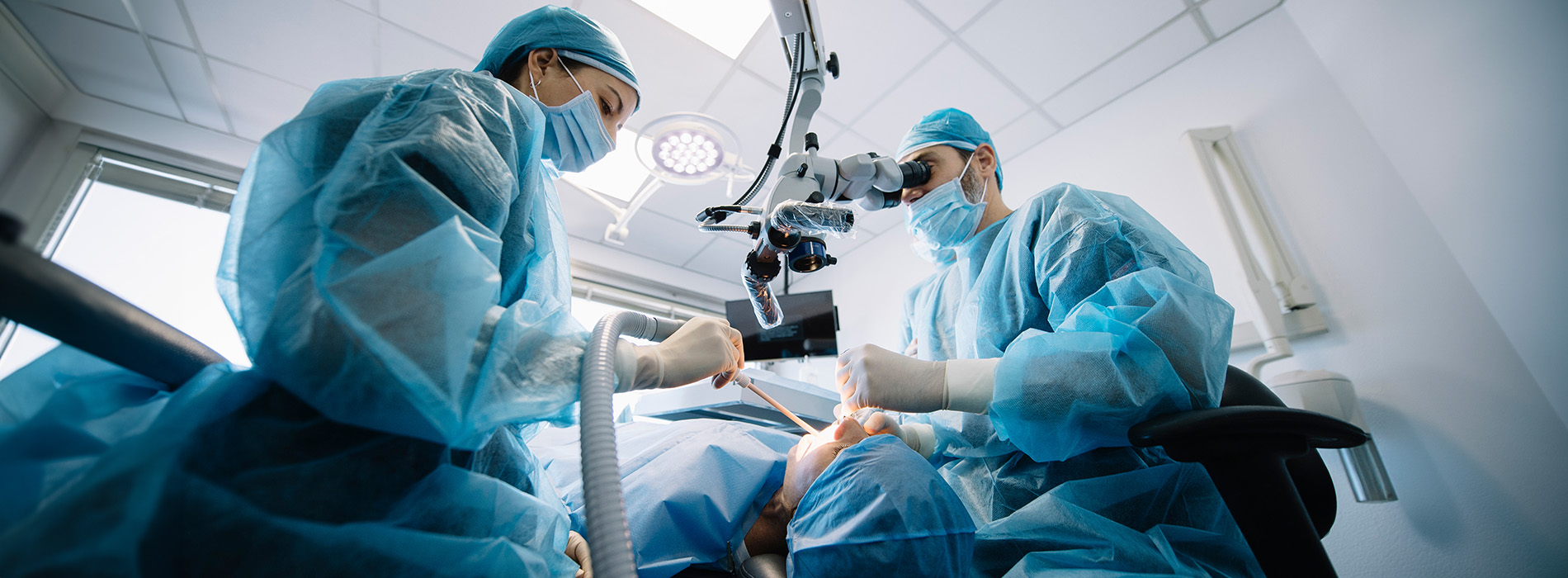 Medical professionals in a surgical room performing surgery with sterile equipment.