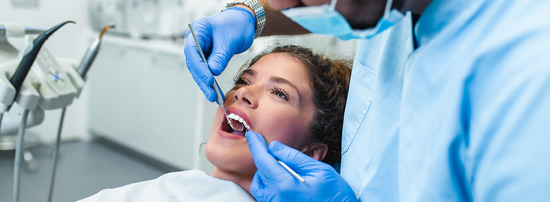 The image shows a dental professional performing oral surgery on a patient with a visible surgical mask and instruments.